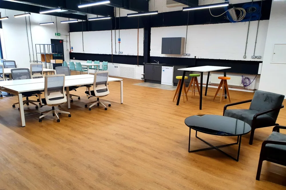 An open-plan office space with wood flooring and a waiting or meeting area.