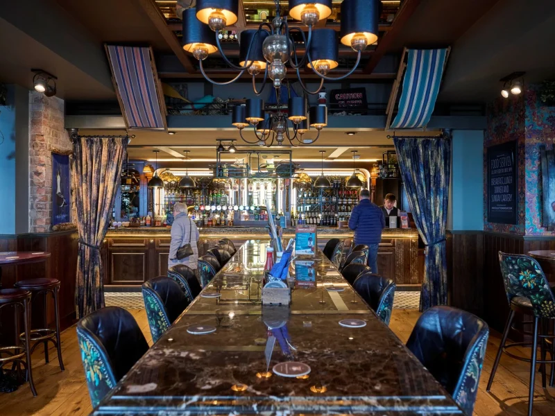 A large, dark Corian dining table with an overhead chandelier.