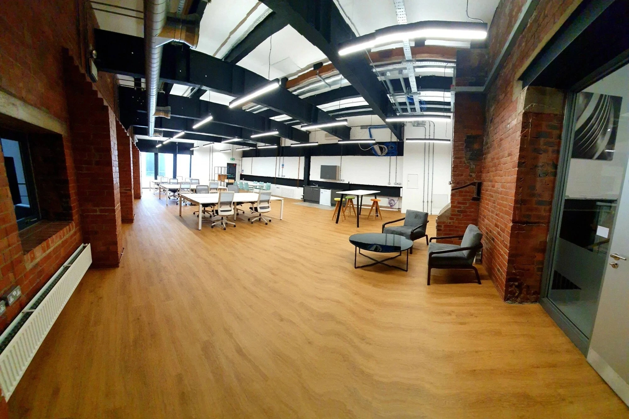Open plan office at Generator Studios, with exposed brick walls and wood flooring. 
