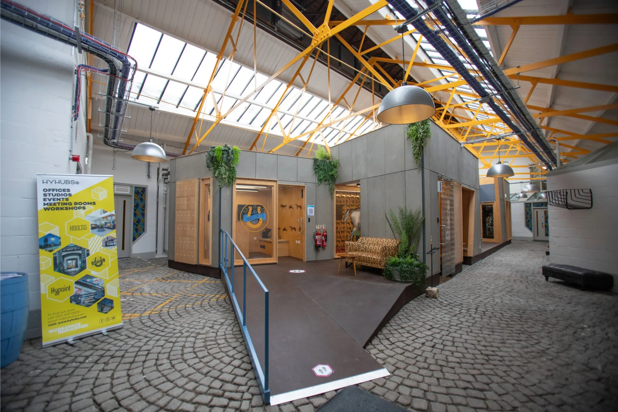 Interior of Haylofts offices in Newcastle, featuring industrial chic workspaces, yellow steel ceiling beams, and cobbled flooring.
