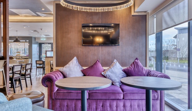 Comfortable lounge area in the restaurant featuring a tufted purple sofa and dark wood panelling.