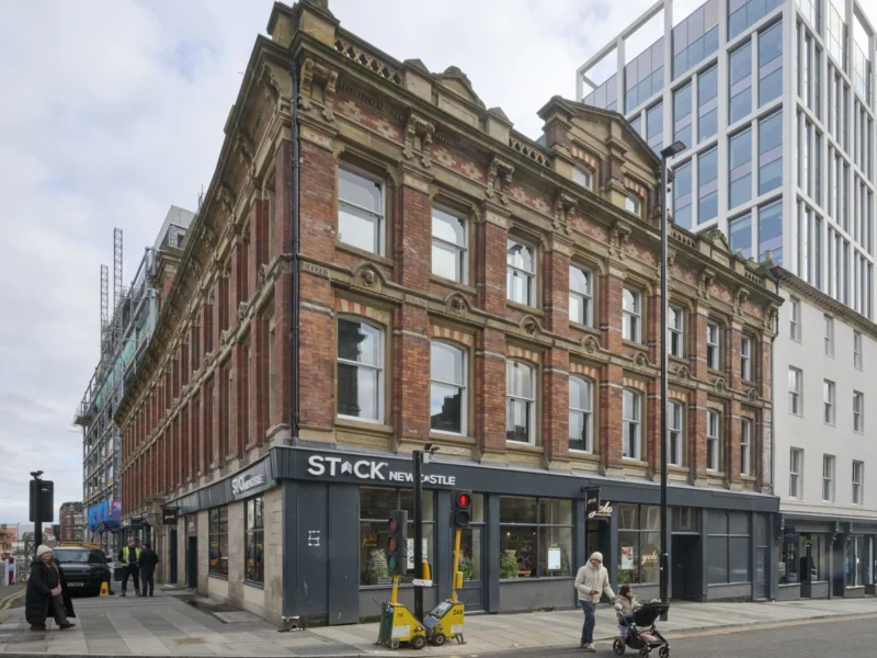 Exterior view of the historic, three-story brick Grade II listed Worswick Chambers building with a modern STACK Newcastle storefront.